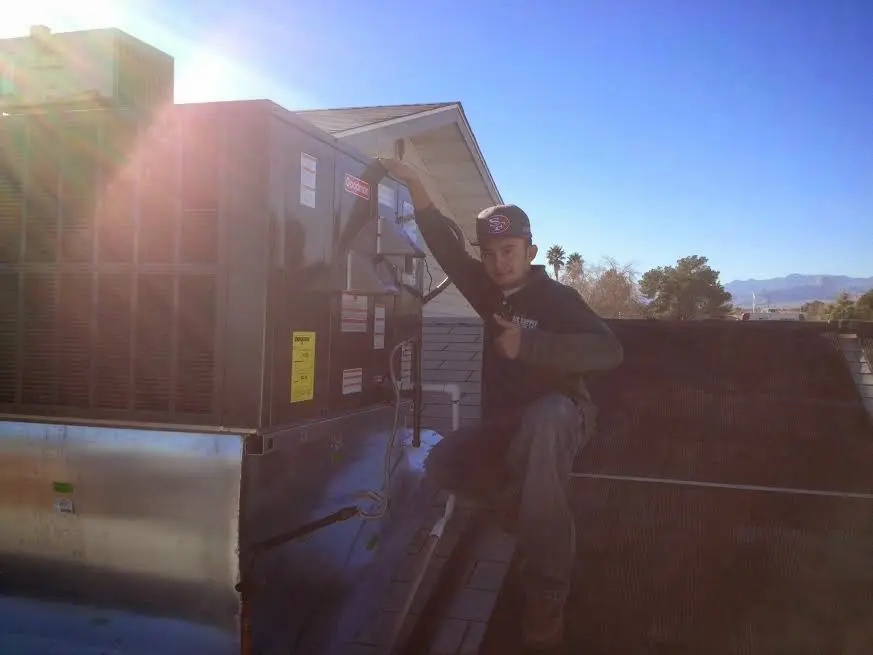 HVAC technician performing AC Tune-Up on a rooftop unit in Fontana